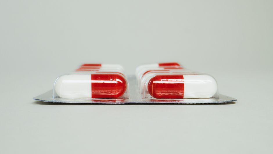 Blister pack of red and white capsules isolated against a simple background.